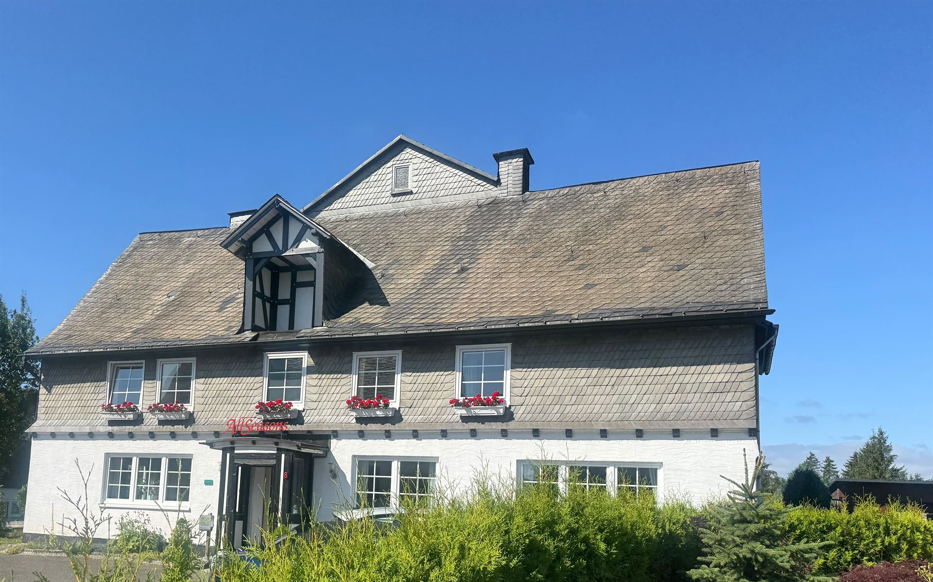 Haus Astenalm in the summer sun with geraniums along the slate facade